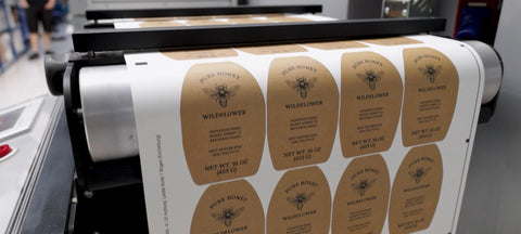 honeystickers-large-video-cover Roll of labels with bee and honeycomb design on a printing machine.